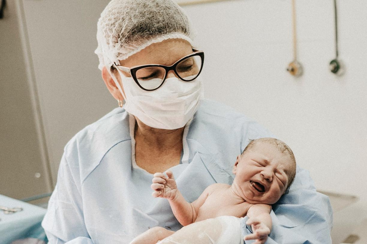 Doctor holding a newborn baby in delivery room.
