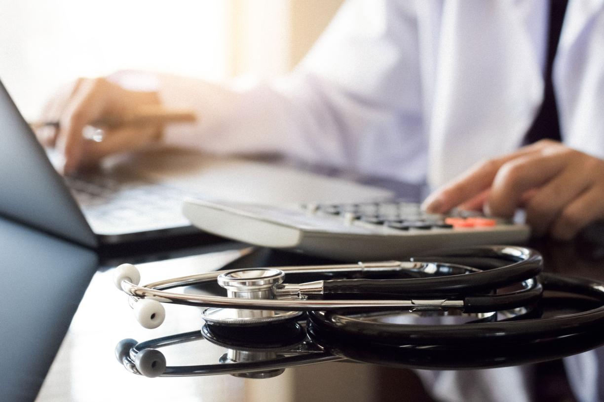 A physician typing on a laptop