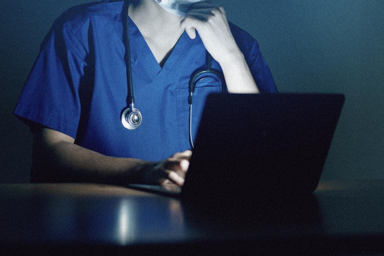Close up of doctor working on laptop late night.