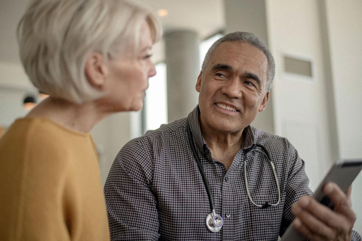 A doctor holding an AI scribe talks with a patient