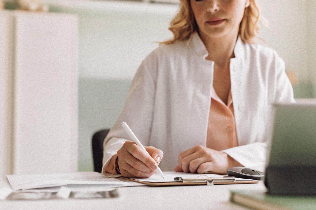 A physician writing a note on their desk