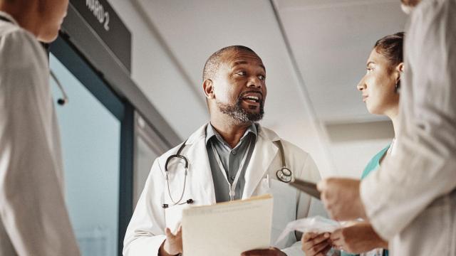A doctor speaking with three other medical staff in a hospital hallway.