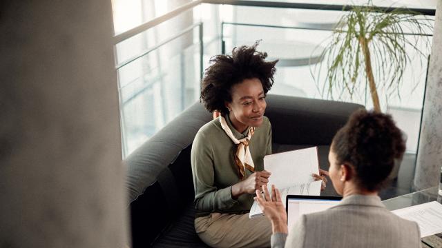 Two people speaking while reviewing documents.